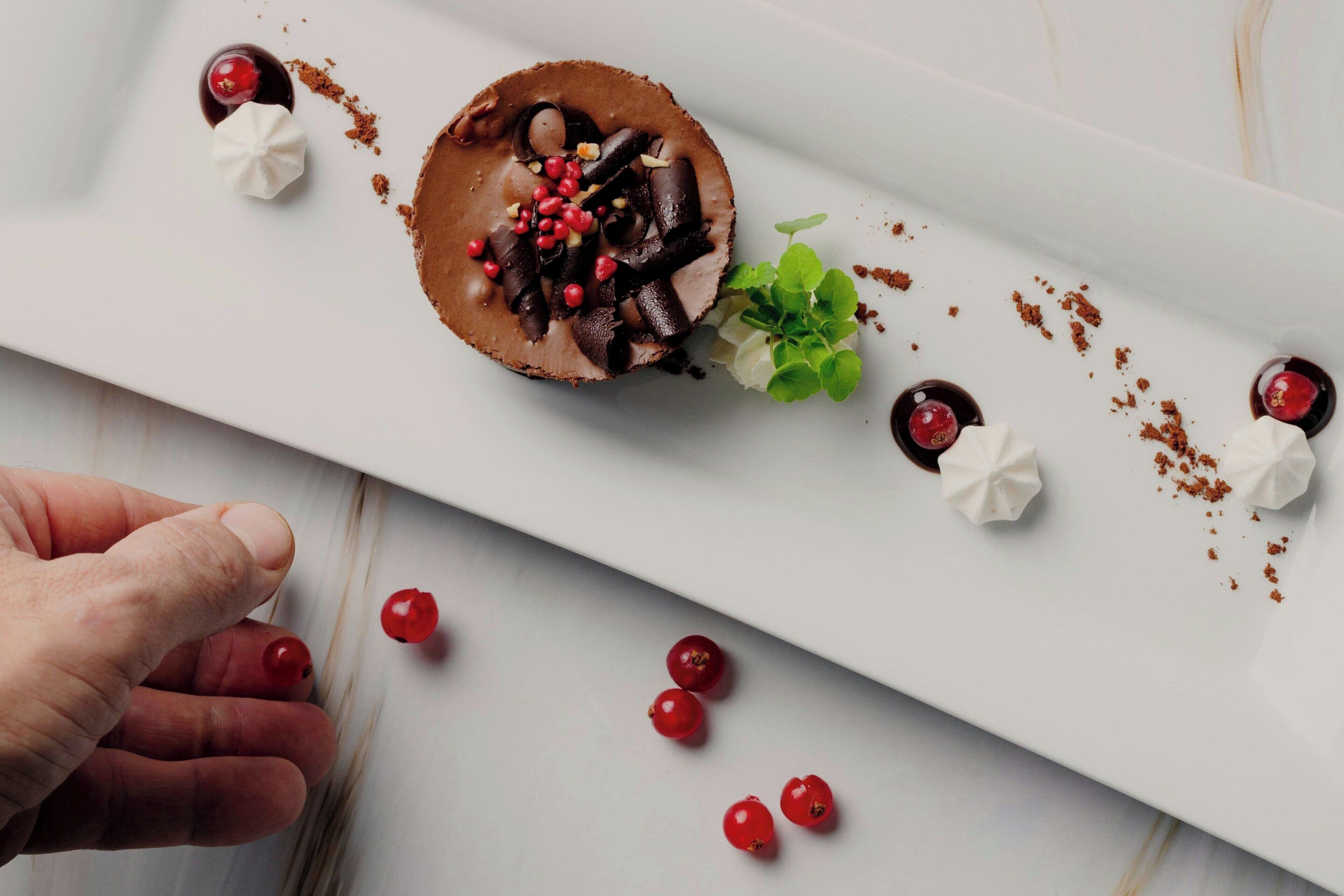 Een nagerechtenbord met chocolademousse, rode bessen en slagroom.