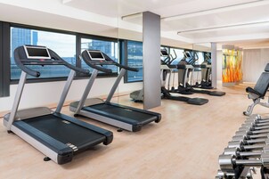 Ein modernes Fitnessstudio mit Laufbändern, Gewichten und Blick auf die Stadt.