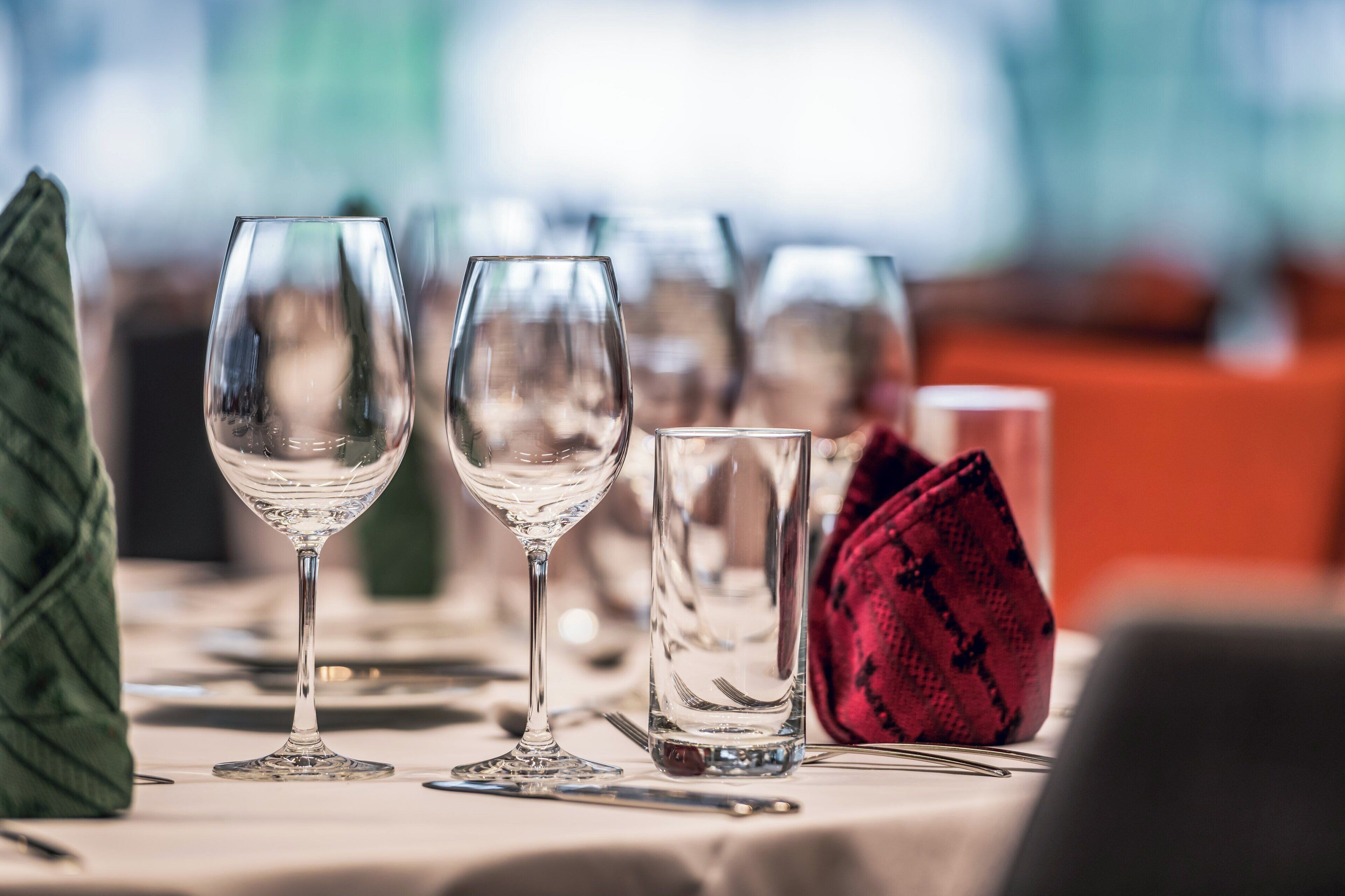 A table set with wine glasses, a water glass, and a red napkin.
