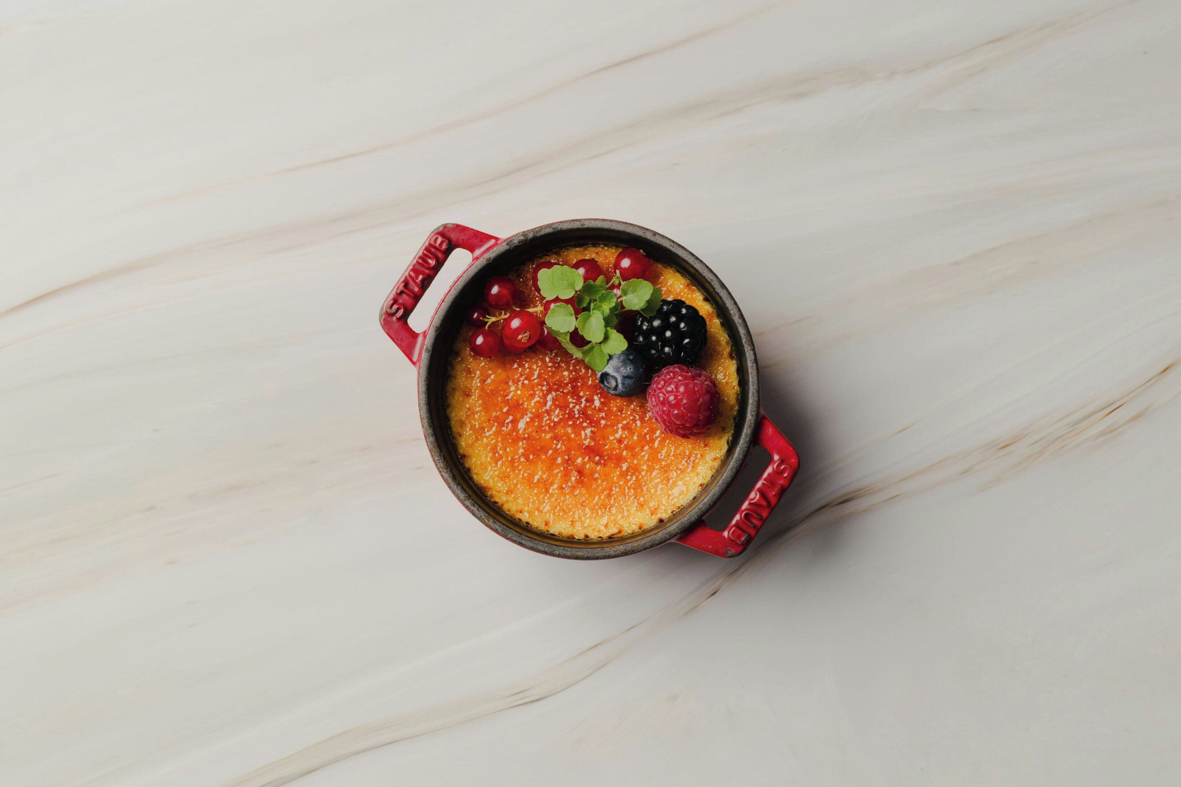 Een dessert in een rode pot op een marmeren oppervlak.