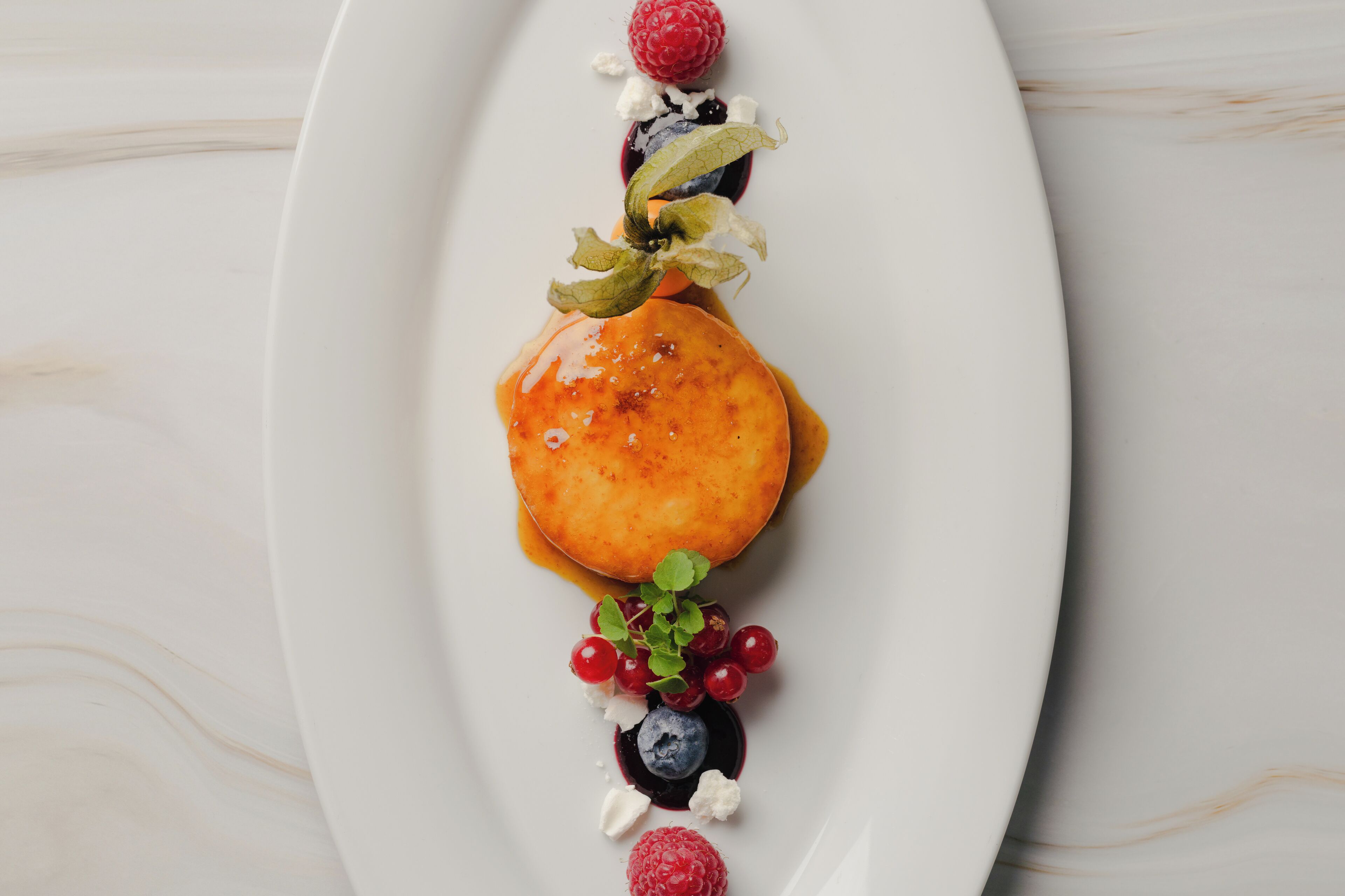 Un postre sobre un plato blanco con un fondo de mármol.