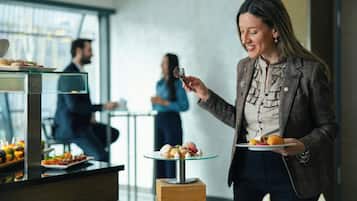A buffet setup with various food items and a person serving.