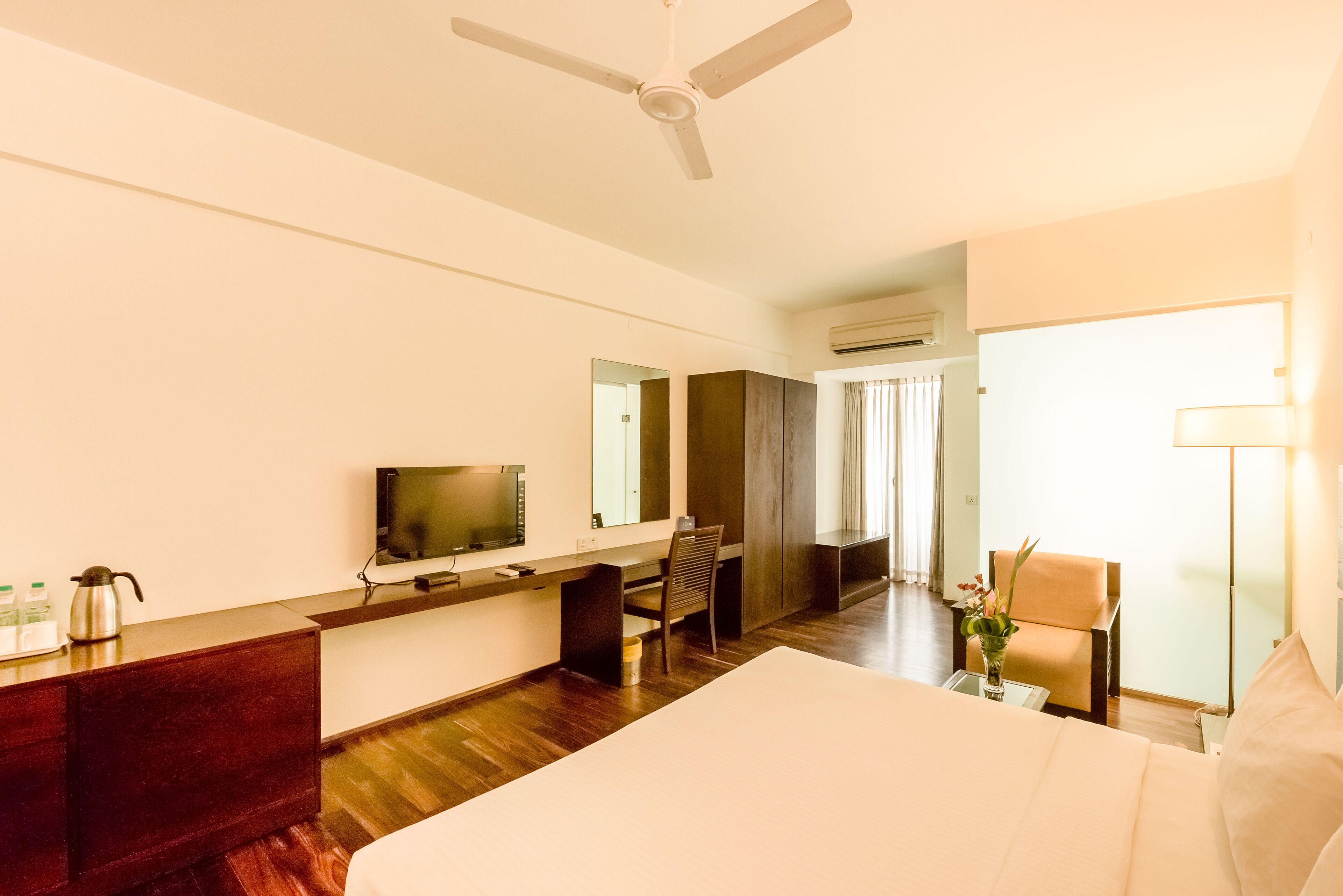A hotel room with a bed, desk, chair, TV, and a ceiling fan.