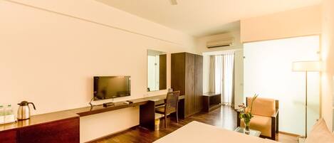 A hotel room with a bed, desk, chair, TV, and a ceiling fan.