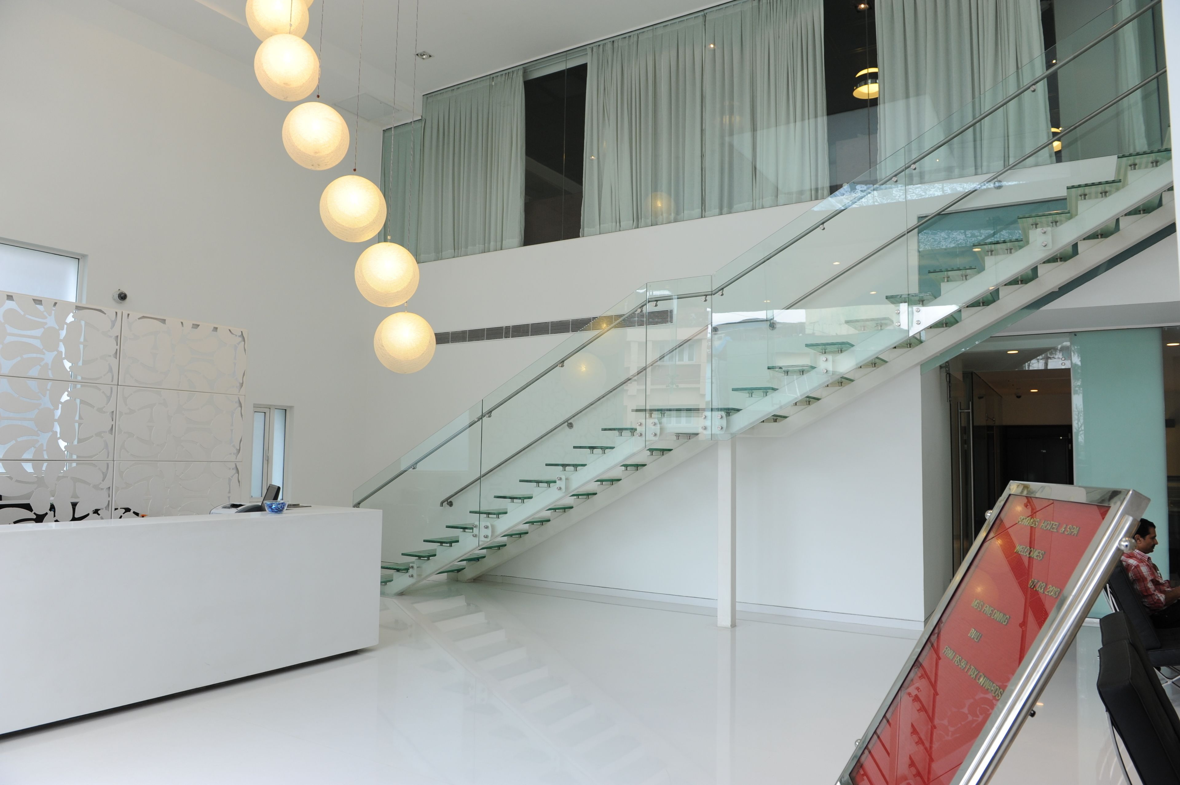 A modern interior with a glass staircase, a reception desk, and a large glass wall.