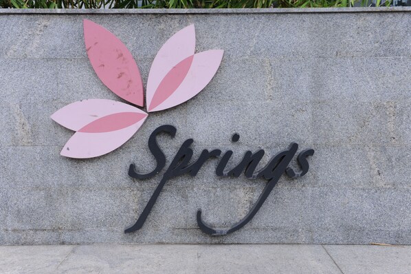 A sign with the word "Springs" and a stylized flower design. - SRS Springs Hotel & Spa (Bengaluru)