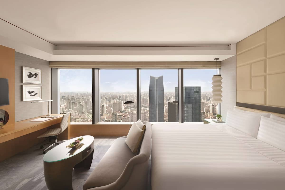 Una habitación de hotel moderna con una cama grande, un escritorio y vistas a la ciudad.