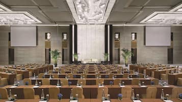 A conference room with rows of tables, chairs, and a stage.