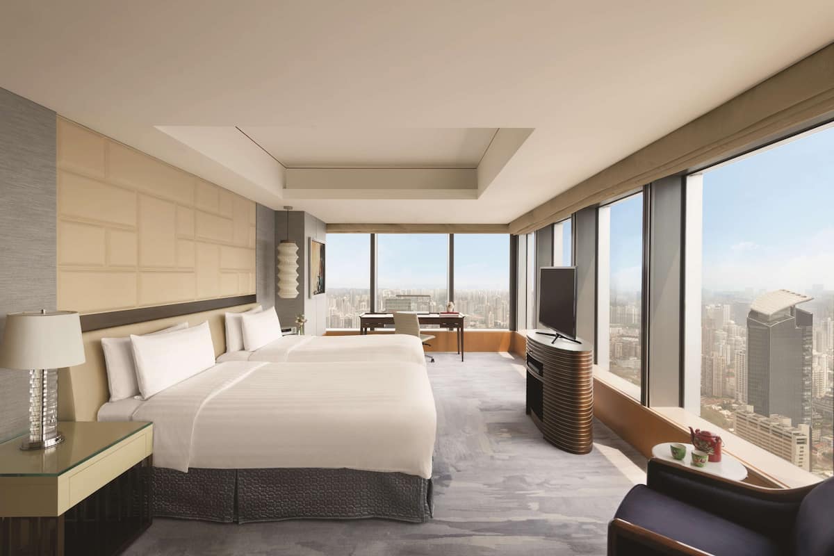 Una habitación de hotel moderna con una cama grande, un escritorio y vistas a la ciudad.