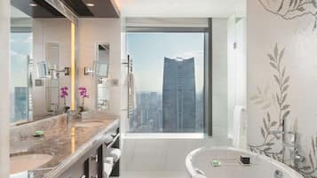 Un baño moderno con un espejo grande, dos lavamanos, una bañera y vistas a la ciudad.