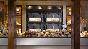 A bakery display with various breads and pastries, wooden beams, and a tiled wall in the background.