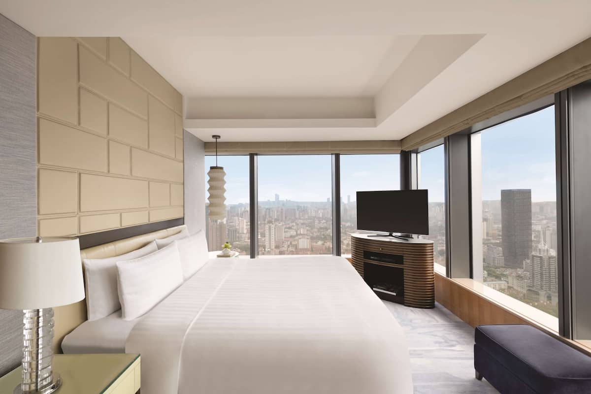 Una habitación de hotel moderna con una cama grande, televisión y vistas a la ciudad.
