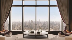 A modern room with a large window offering a city view, a round table with two decorative items, and a sofa with cushions. - Jing An Shangri-La, Shanghai (Shanghai)