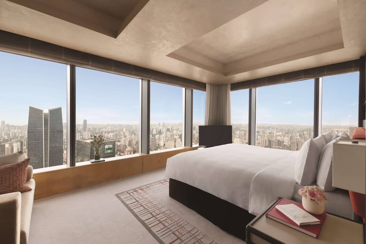 Una habitación de hotel moderna con una cama grande, televisión y vistas a la ciudad.