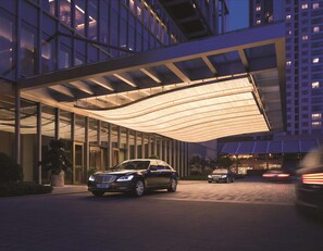 A modern hotel entrance with a covered walkway and luxury cars parked in front. - Jing An Shangri-La, Shanghai (Shanghai)