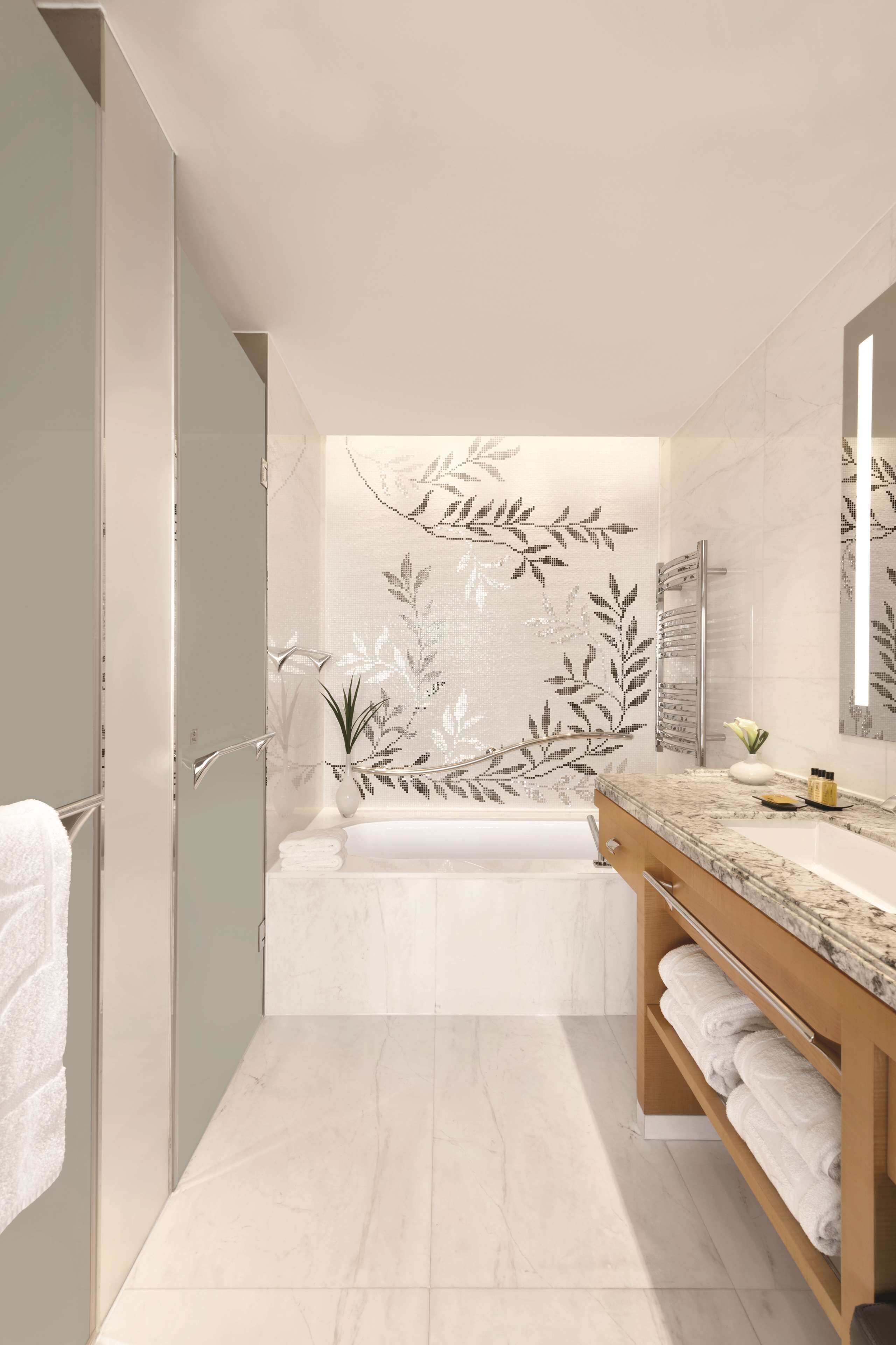 A modern bathroom with a bathtub, a wooden vanity, and a large mirror.
