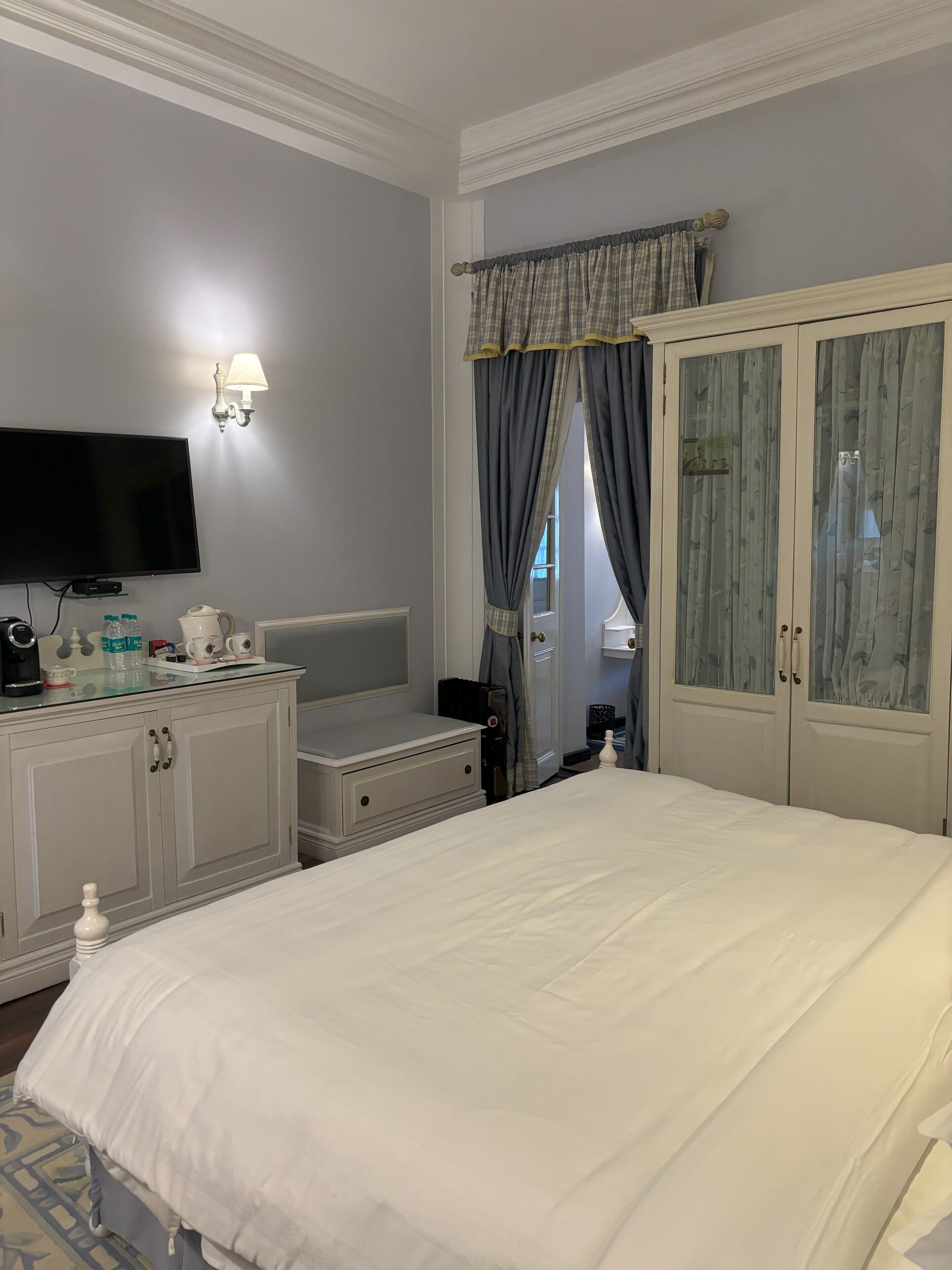 A hotel room with a bed, a TV, a dresser, and a wardrobe.