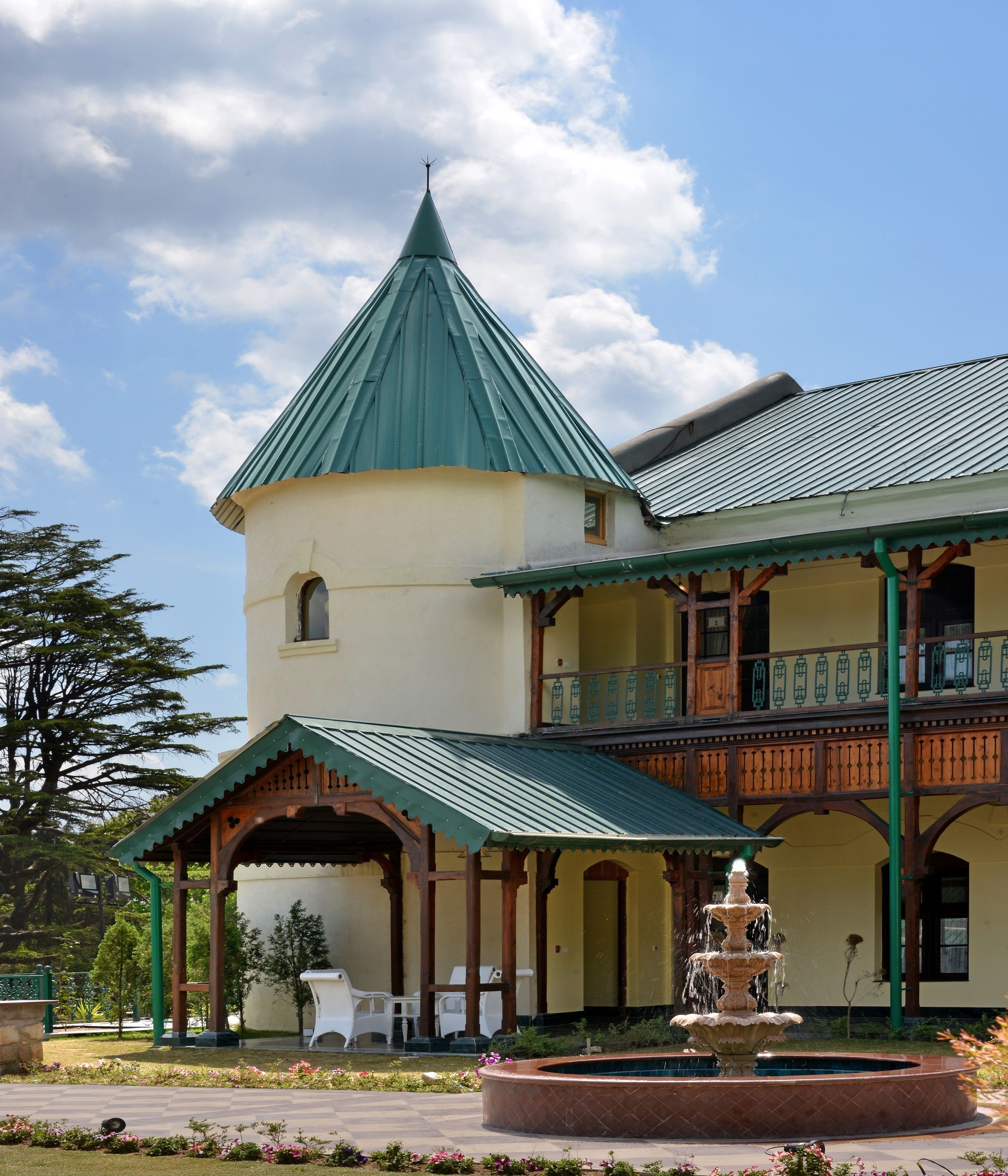 A building with a green roof, a tower, and a balcony with railings.
