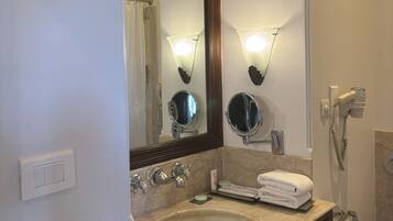 A bathroom with a large mirror, a sink, a towel rack, and a handheld showerhead.