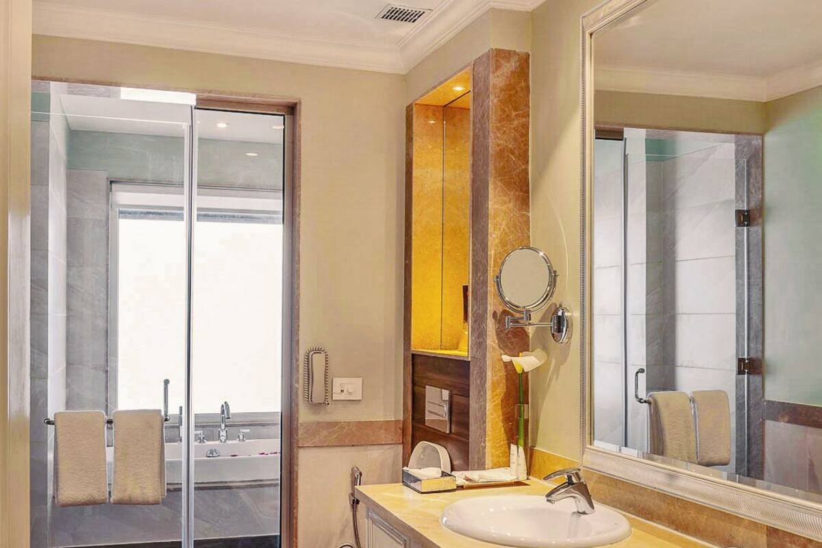 A modern bathroom with two sinks, a large mirror, and a shower area.