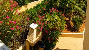 A garden with various plants and a small structure, overlooking a residential area and the sea. - Astir Studios (Hersonissos)