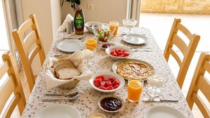 A dining table set with various dishes, including watermelon, bread, and a salad, with chairs around it. - Astir Studios (Hersonissos)