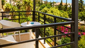 A balcony with a table and chairs, overlooking a hillside with greenery and buildings. - Astir Studios (Hersonissos)