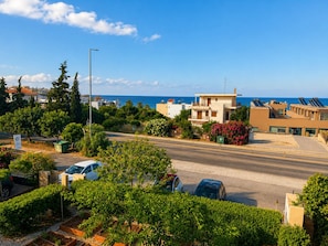 A coastal residential area with houses, a road, and parked cars. - Astir Studios (Hersonissos)