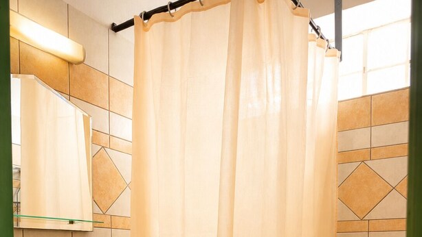 A bathroom with a sink, toilet, and shower curtain. - Astir Studios (Hersonissos)