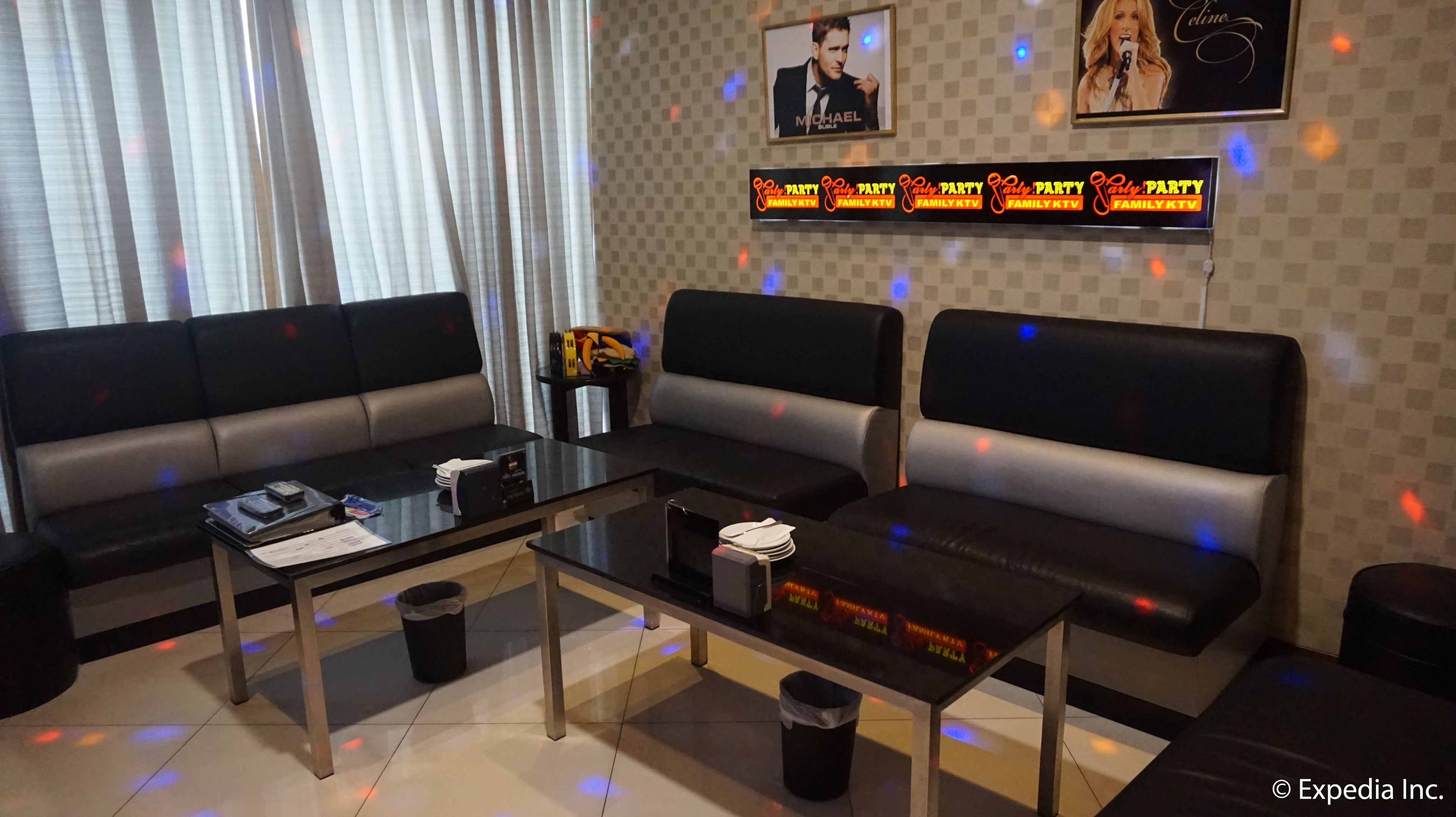A modern lounge area with a sofa set, a glass-top coffee table, and a wall-mounted TV displaying 'Family KTV'.