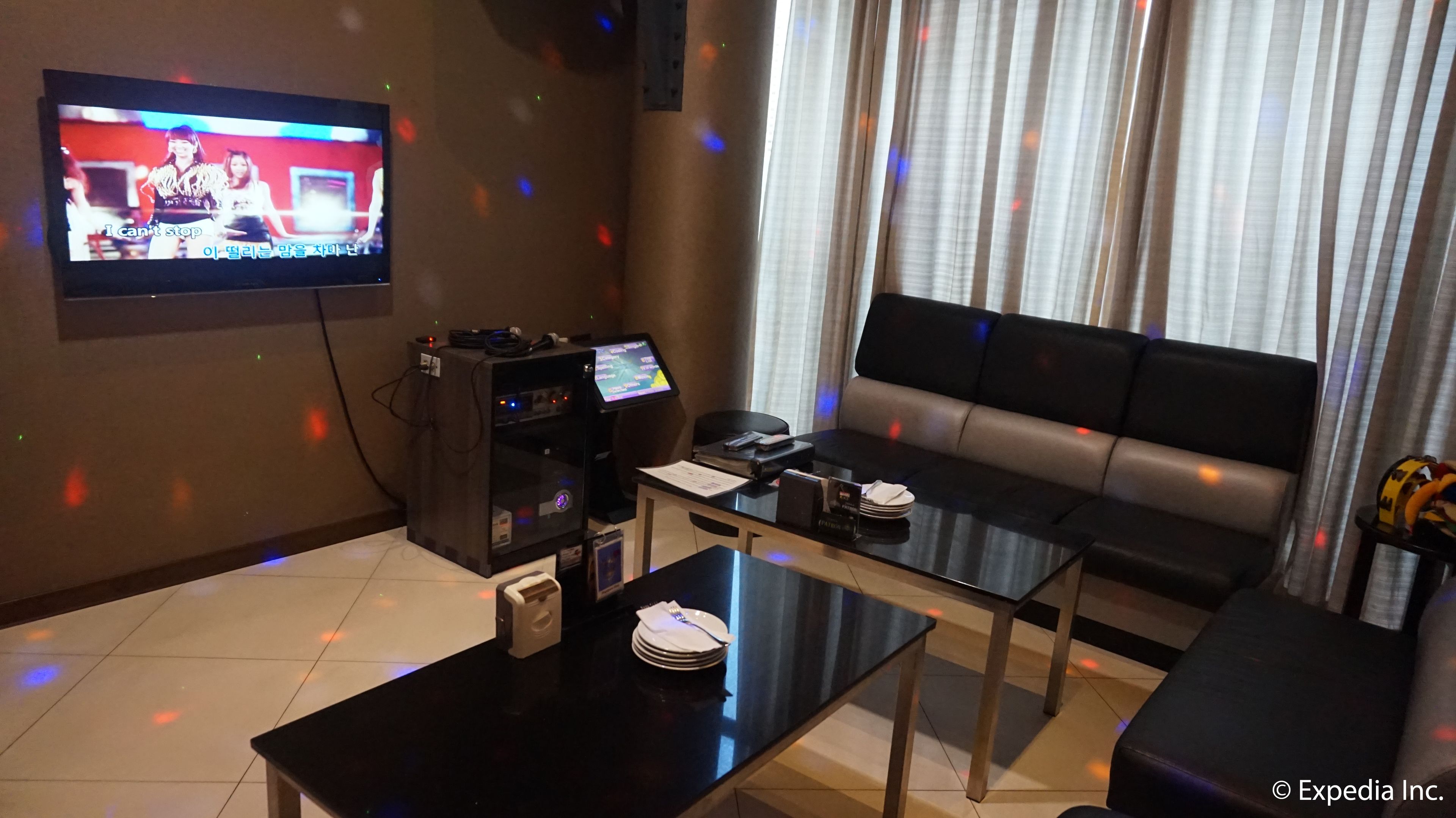 Ein modernes Wohnzimmer mit einem Wand-Fernseher, einem Sofa, einem Couchtisch und einem kleinen Tisch mit einer Speisekarte.