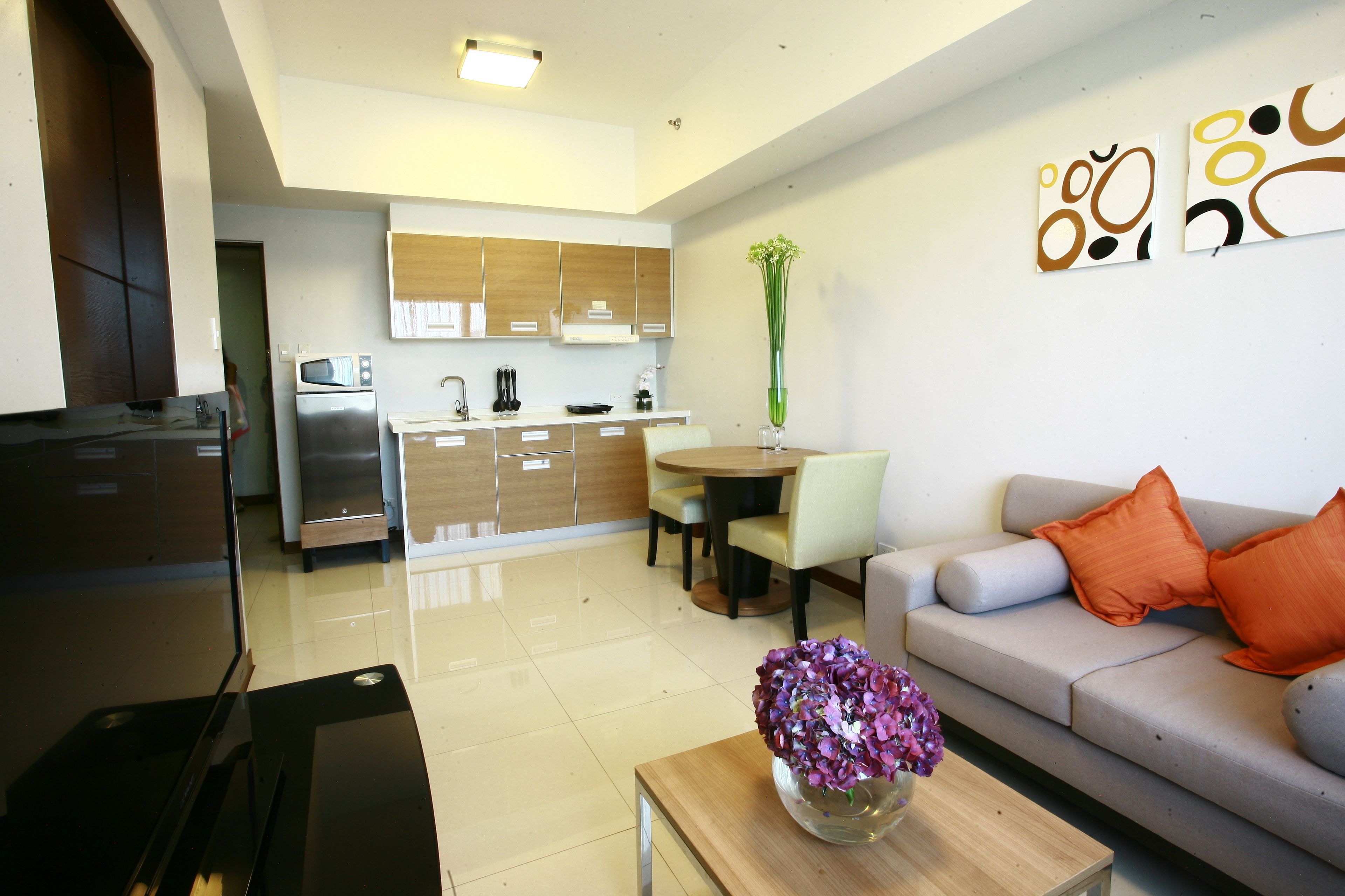 A modern living room with a sofa, coffee table, and a dining area with chairs and a table.
