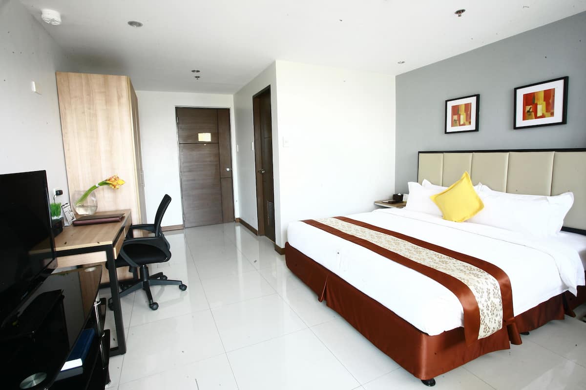 Ein Hotelzimmer mit Bett, Schreibtisch, Stuhl und Fernseher.