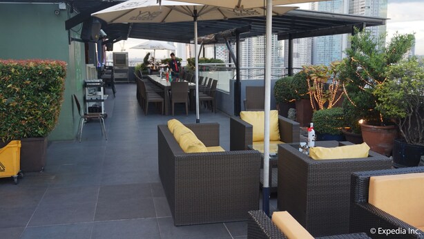 A rooftop patio with outdoor seating, potted plants, and umbrellas. - Ace Hotel & Suites (Pasig)