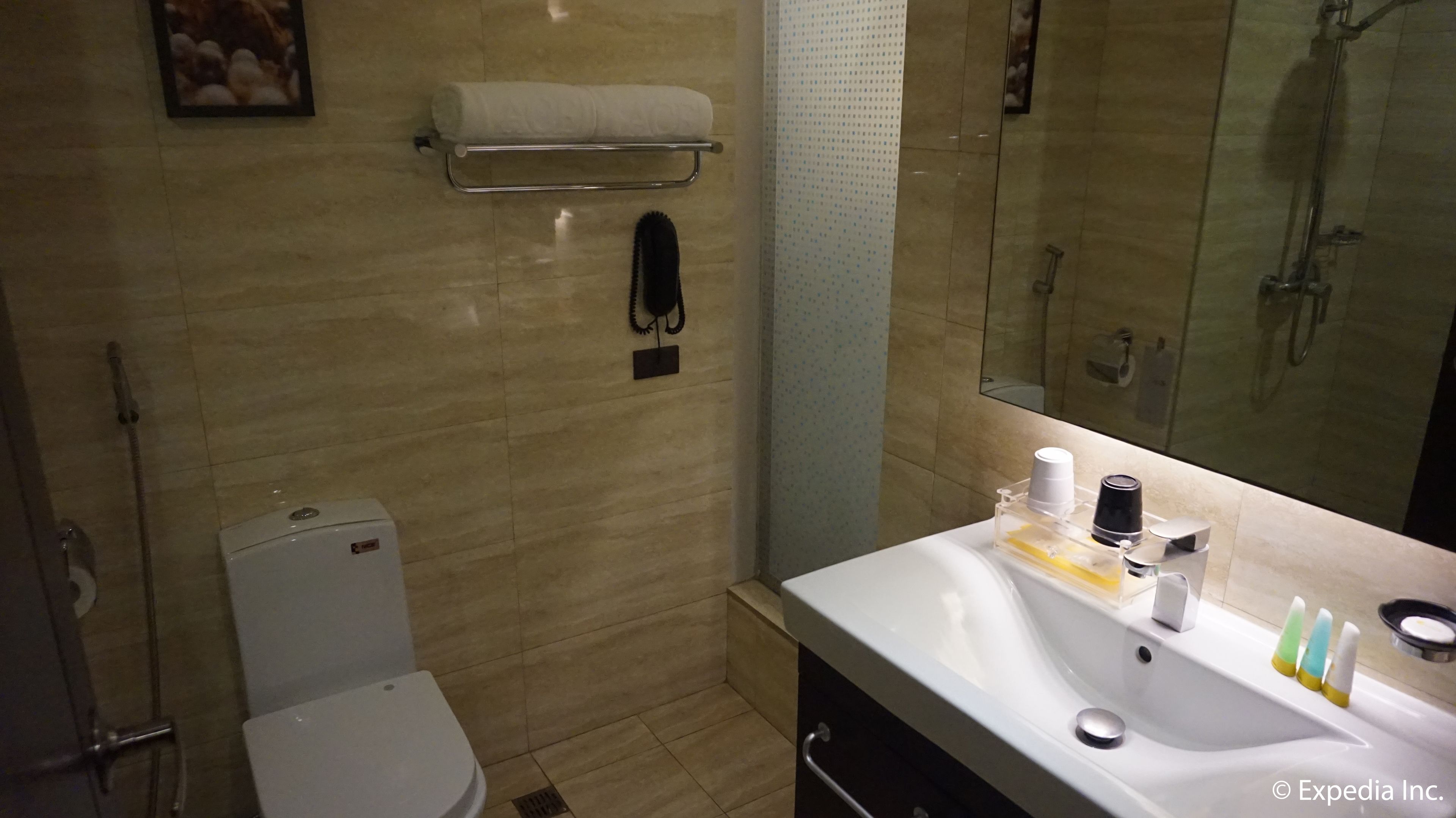 A bathroom with a toilet, sink, and shower. There is a towel rack above the toilet and a mirror above the sink.