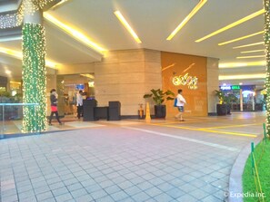 A modern hotel lobby with a reception desk, a large illuminated sign, and a potted plant. - Ace Hotel & Suites (Pasig)
