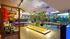 A buffet setup with a central island, various food items, and a decorative tree. - Ace Hotel & Suites (Pasig)