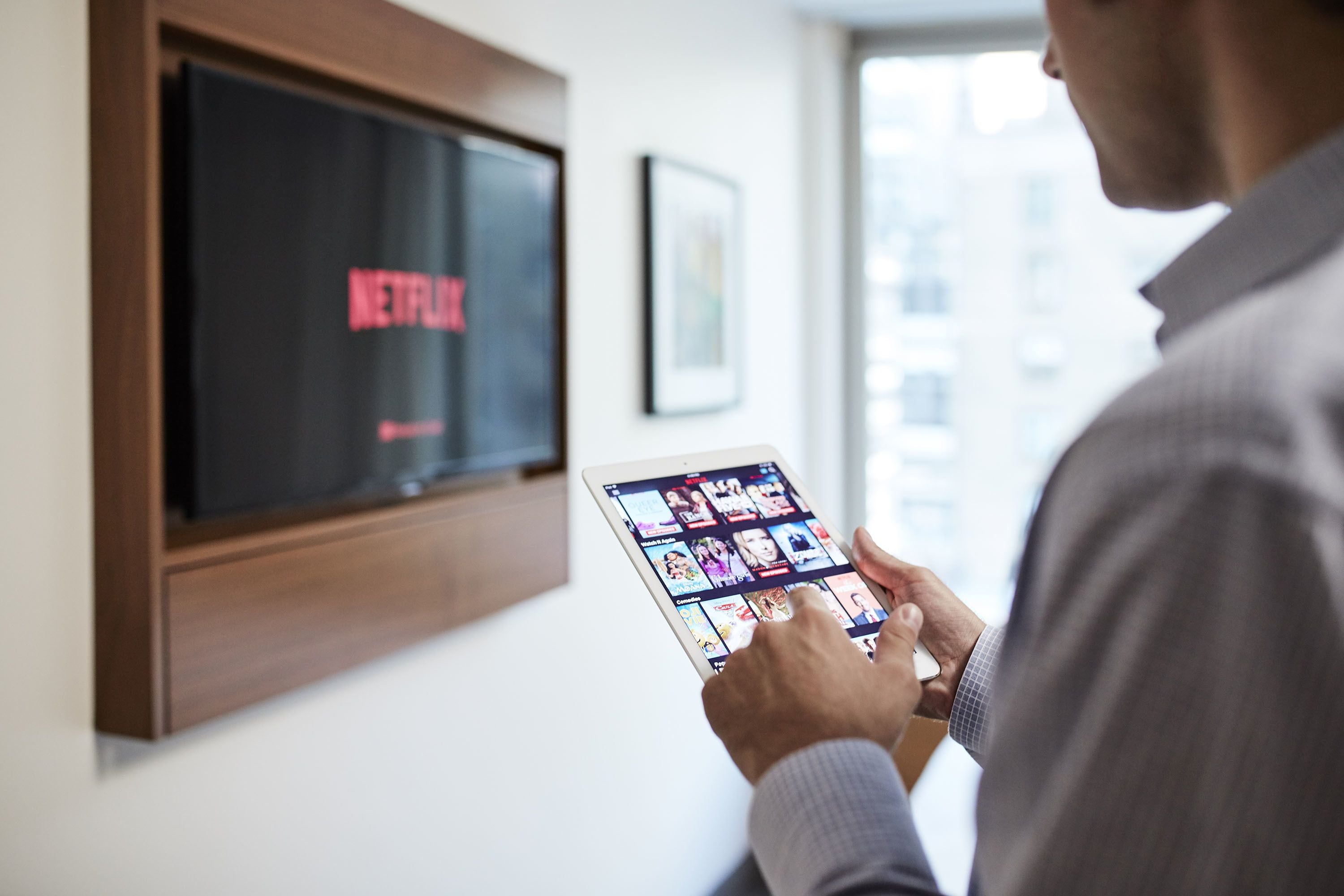 A person using a tablet with a Netflix interface.