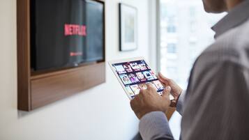 A person using a tablet with a Netflix interface.