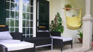 Eine Terrasse mit Korbmöbeln, einer Hängematte und Blumentöpfen.