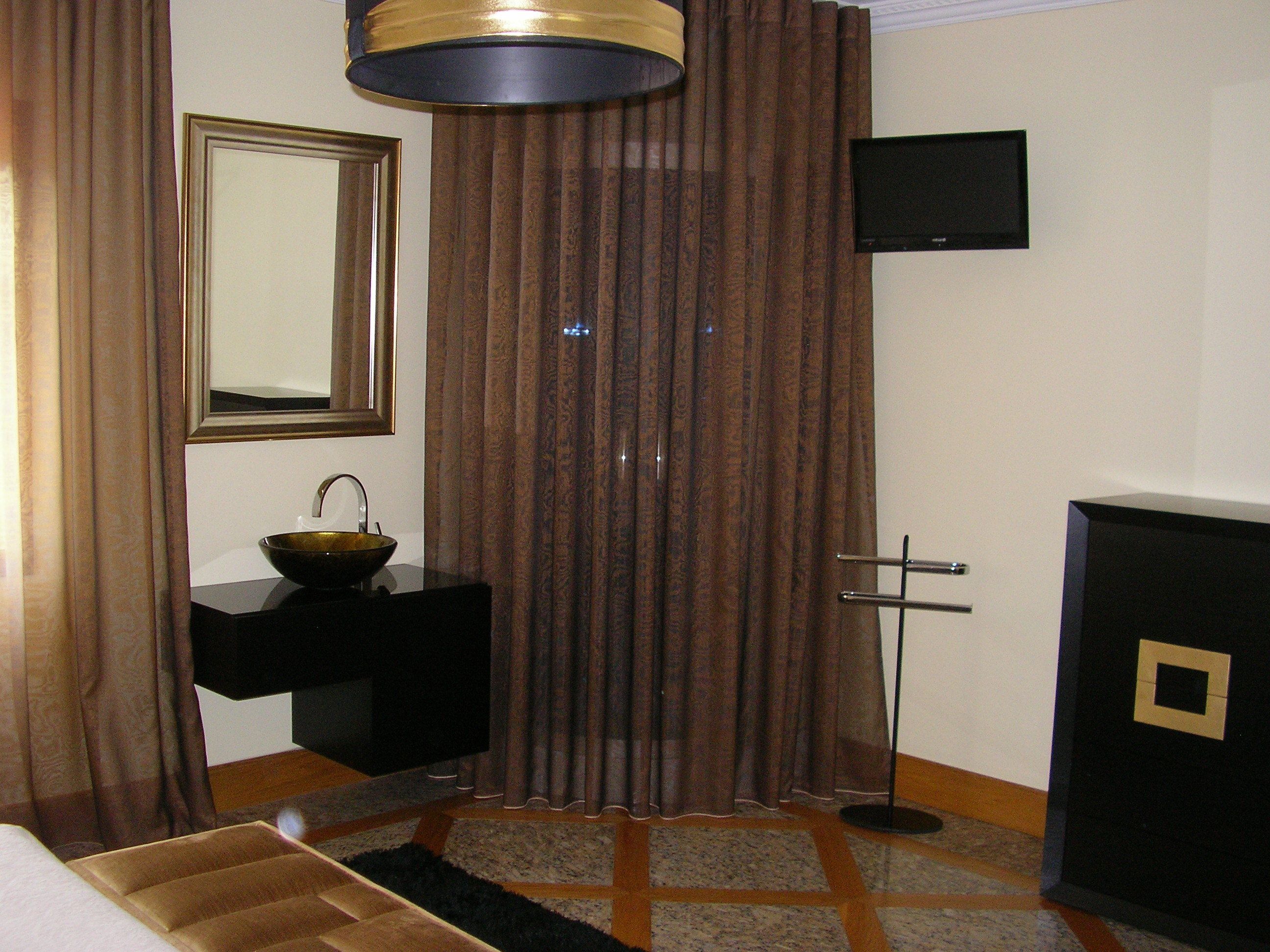 A hotel room with a large mirror, a black sink, a bowl, a television, and a cabinet.