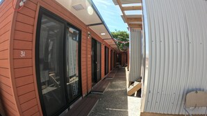 Una hilera de cabañas con grandes puertas correderas, un espacio exterior cubierto y un pequeño banco de madera.