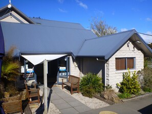 A building with a reception area, a covered entrance, and outdoor seating. - Kaiteri Lodge (Kaiteriteri)