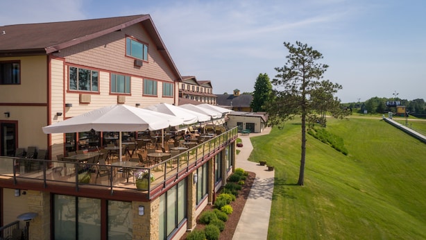 Ein Hotel mit Außenbereich, einer wintergartenartigen Veranda und Blick auf einen Golfplatz.