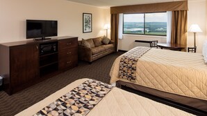 Ein Hotelzimmer mit Bett, Sofa, Fernseher, Schreibtisch und einem Fenster mit Blick.