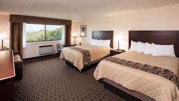 Habitación de hotel con dos camas, un escritorio, una silla, una ventana con vistas y una lámpara.