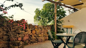 A stone wall with climbing plants and a table with chairs. - Sa Corti De Sa Perda (Piscinas)
