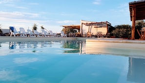 A swimming pool with lounge chairs and a shaded area. - Sa Corti De Sa Perda (Piscinas)