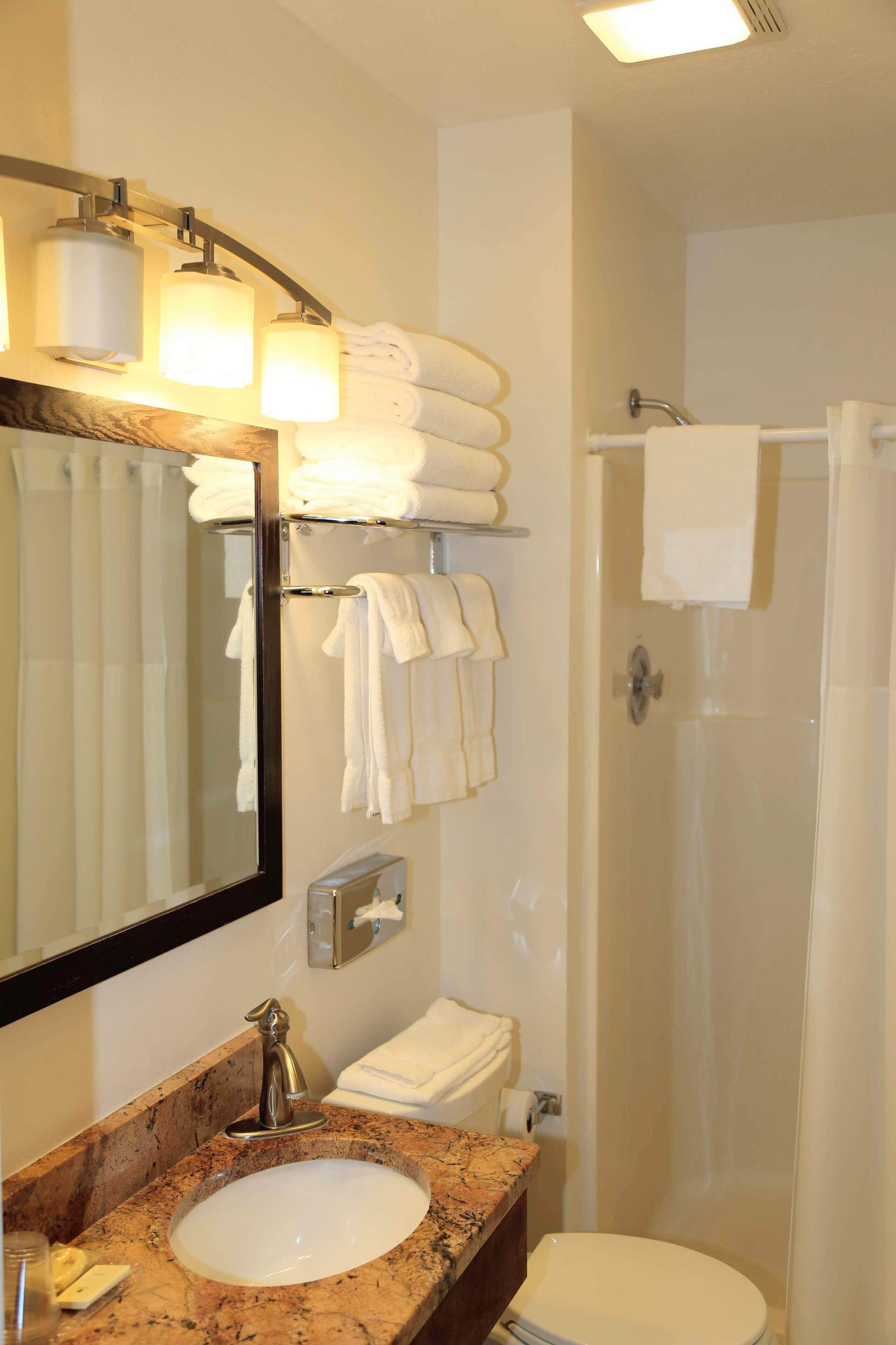 A bathroom with a sink, mirror, towel rack, and shower.