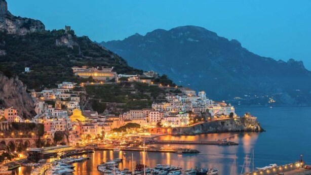 A coastal town with buildings on a hillside, a marina with boats, and a mountain backdrop. - B&B Elena (Pompei)